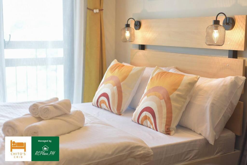 a bed with white sheets and pillows on it at RcplacePH T3-413- Pinesuites Tagaytay in Tagaytay