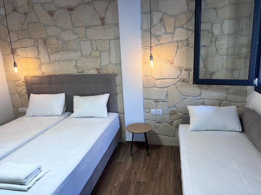two beds in a room with a stone wall at Naria Studios in Skala Fourkas