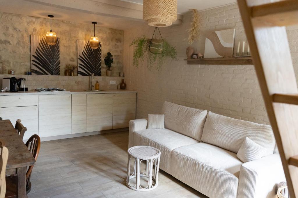 un salon avec un canapé blanc et une cuisine dans l'établissement Le Petit Gîte - La Nouvelle Histoire, à Graignes