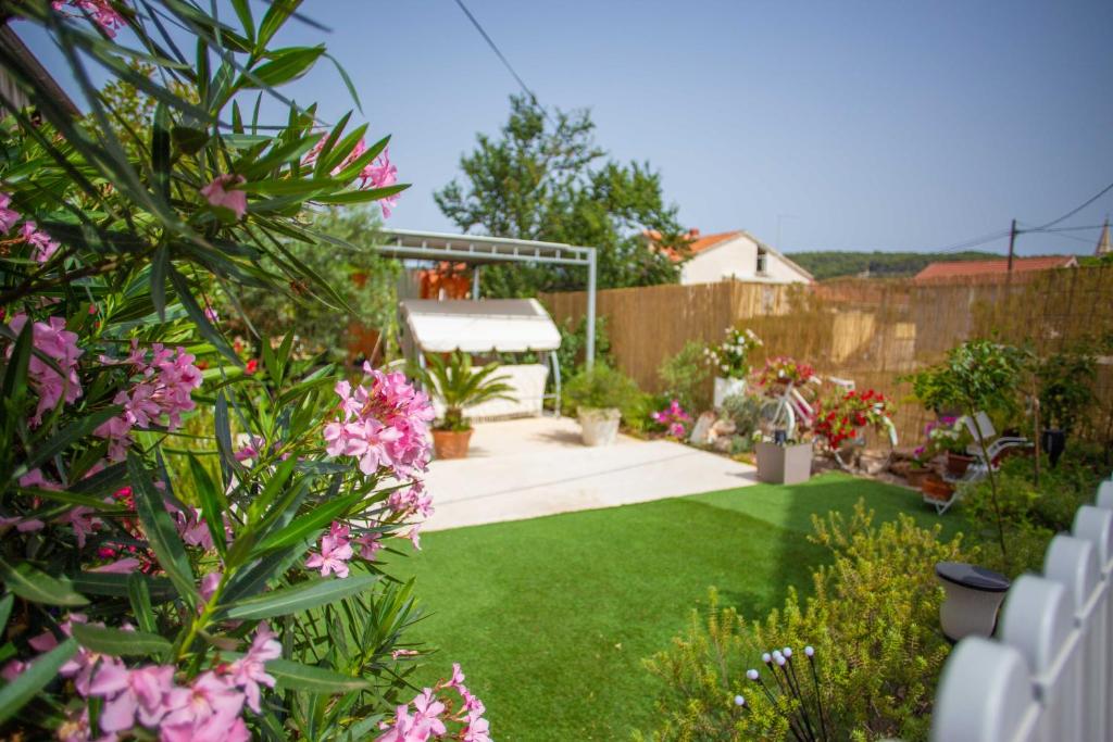 a garden with green grass and pink flowers at Villa Rosa in Jelsa