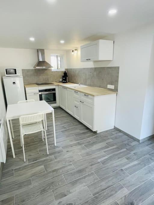 - une cuisine avec des appareils blancs, une table et des chaises dans l'établissement Maison calme - proche Tricastin, à Bollène