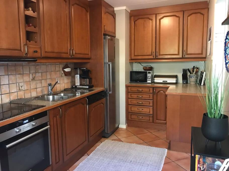 Una cocina con gabinetes de madera y un refrigerador de acero inoxidable. en Hessahuset, en Ålesund