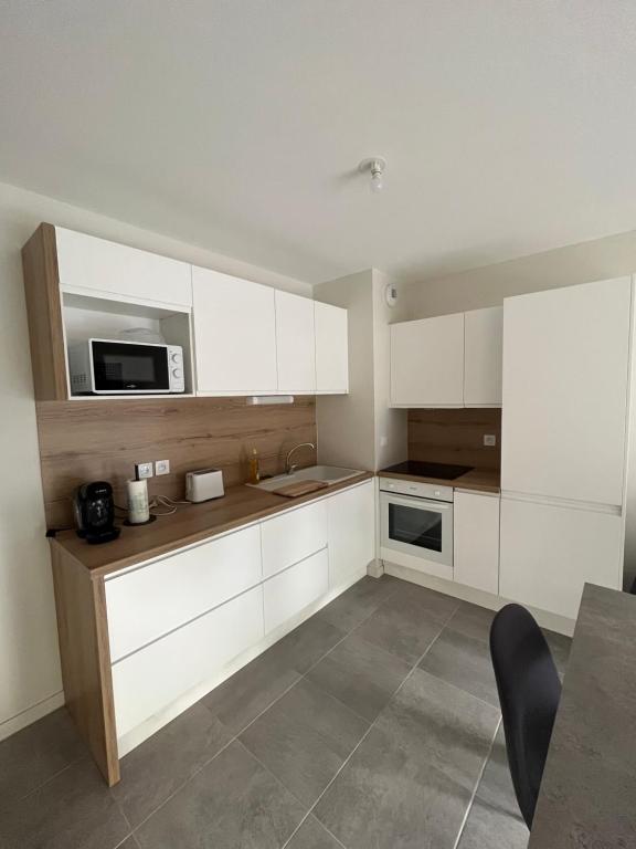 une cuisine avec des armoires blanches et un micro-ondes dans l'établissement Gare centre ville d'Arcachon, à Arcachon