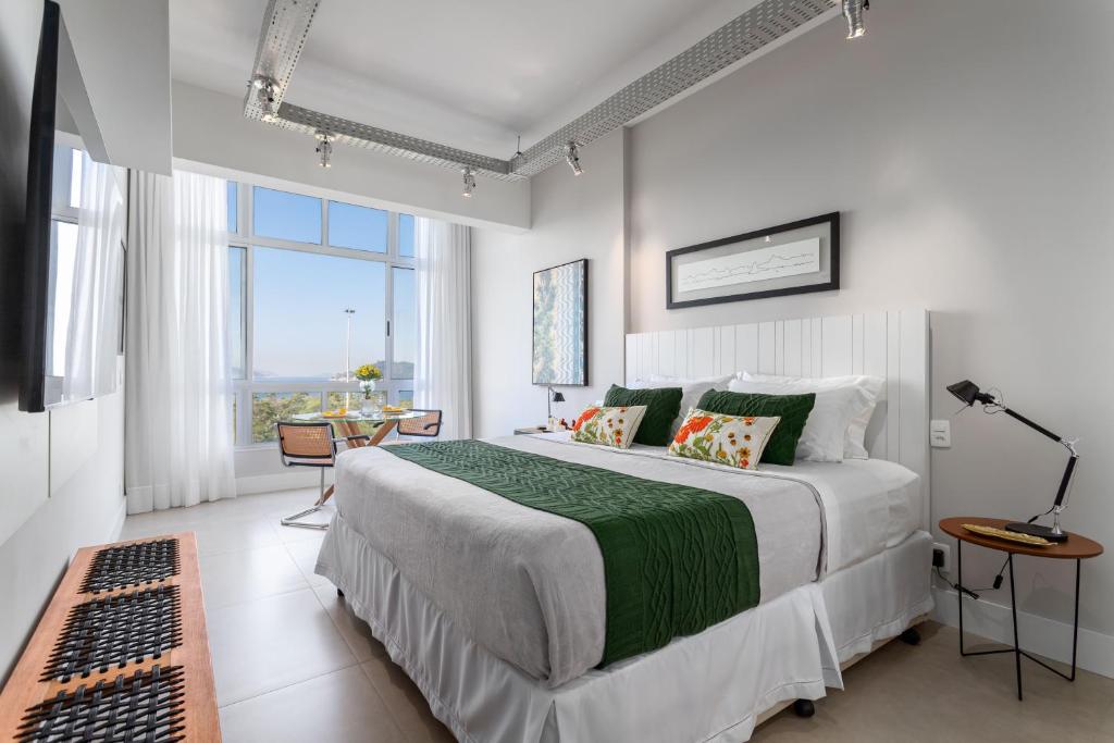 Hotel Reformado e confortável, vista mar no coração do Rio, a bedroom with a large bed with a green blanket at Reformado e confortável, vista mar no coração do Rio in Rio de Janeiro