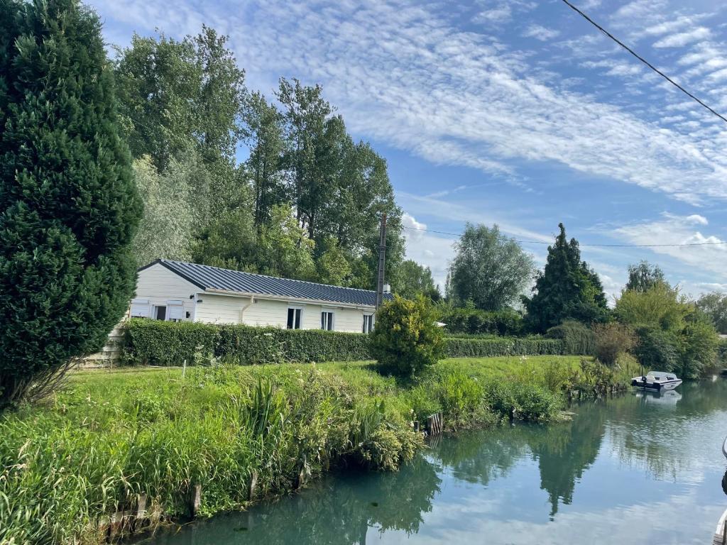 une maison avec une rivière devant elle dans l'établissement La maison du Marais, à Tilques