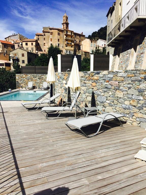 - une rangée de chaises longues avec des parasols et une piscine dans l'établissement Saint Christophe, à Omessa