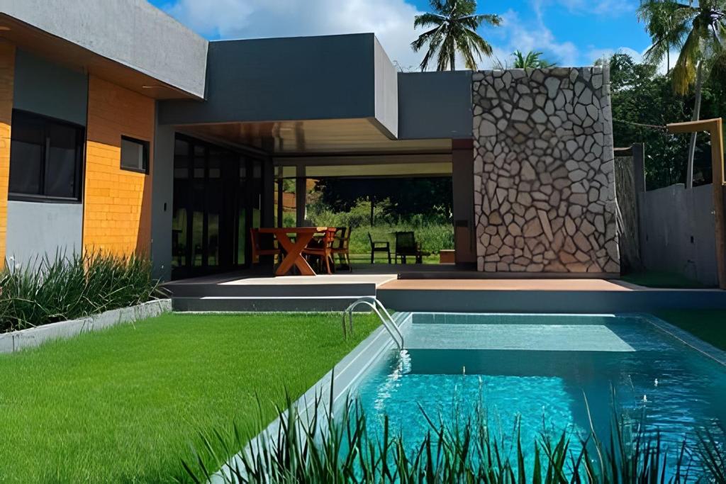 ein Haus mit einem Swimmingpool vor dem Haus in der Unterkunft Casa em Milagres| 3 suítes, área gourmet, piscina in Passo de Camarajibe