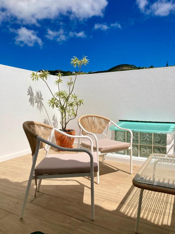 a patio with two chairs and a table and a plant at Cais Inn in Horta