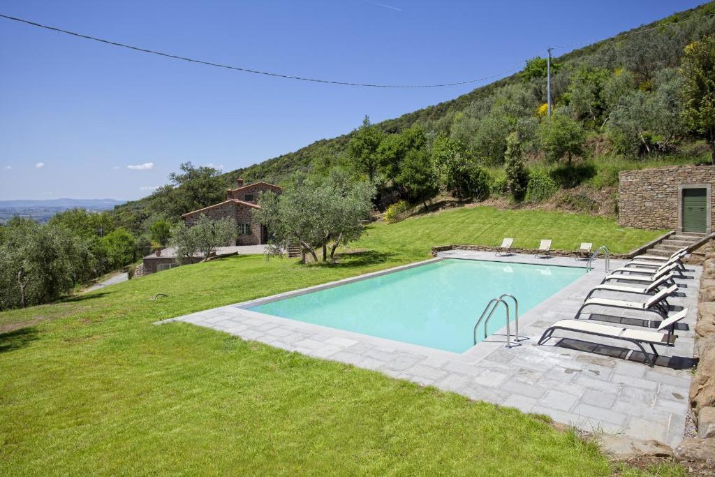 basen na trawiastym polu z domem w obiekcie Villa Il Sole w mieście Cortona