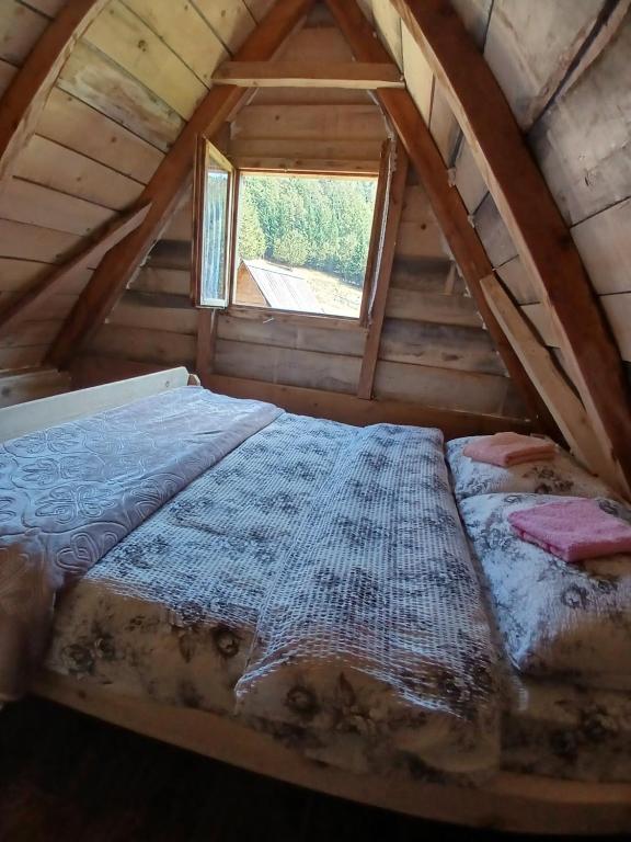 a bed in a attic with a window at Dulović - KATUN POTOCI in Kolašin