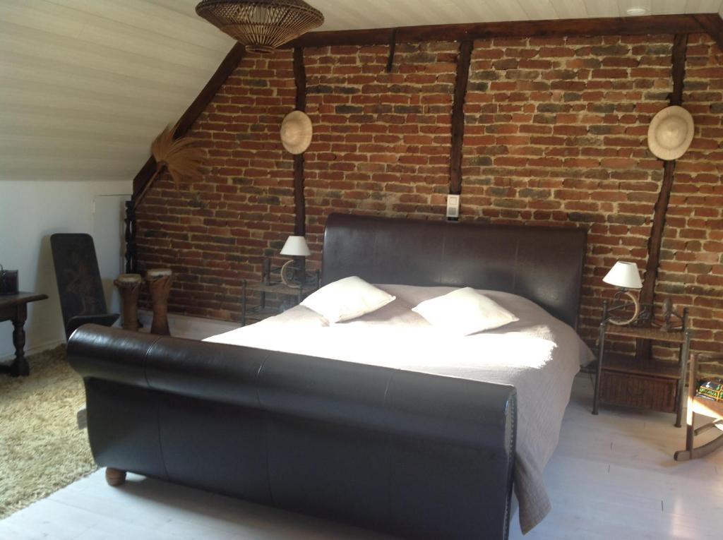 1 dormitorio con cama de cuero negro y pared de ladrillo en Vakantiewoning Ijzerrust, en Roesbrugge-Haringe