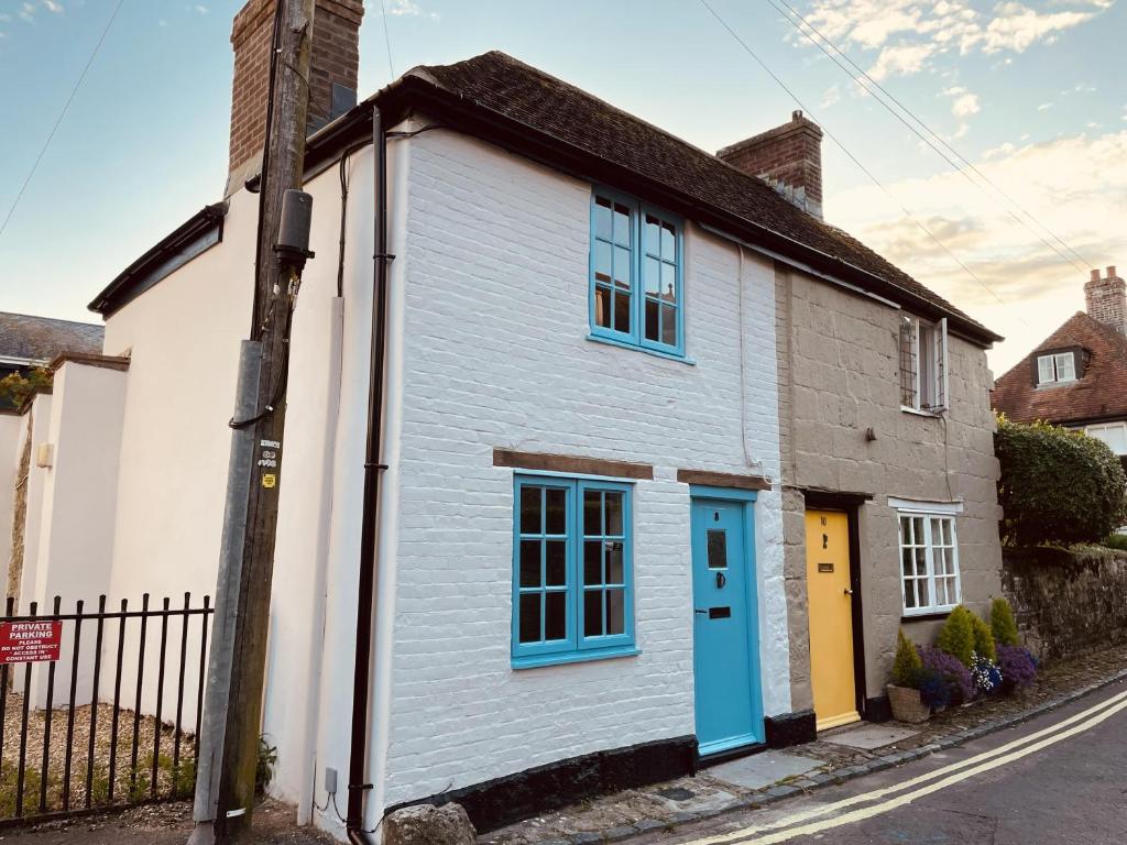 un cottage blanc avec une porte bleue dans une rue dans l'établissement Charming Cottage Sleeps 4 with Sauna, à Shaftesbury