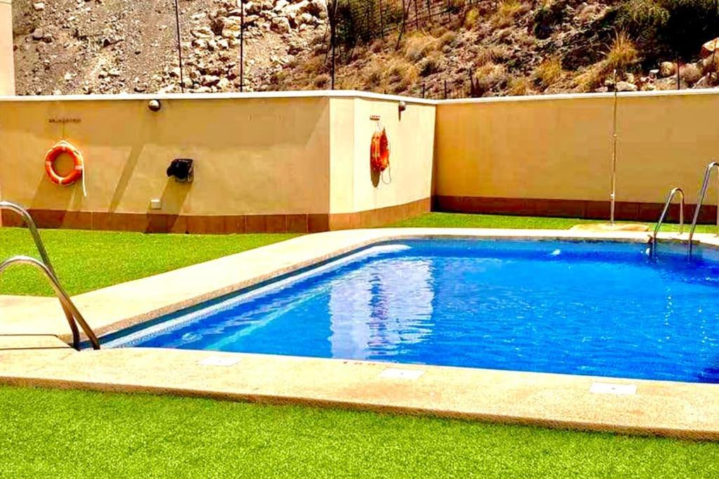 a swimming pool in a yard with green grass at KS Maral Home - Kaleria Suites in Aguadulce