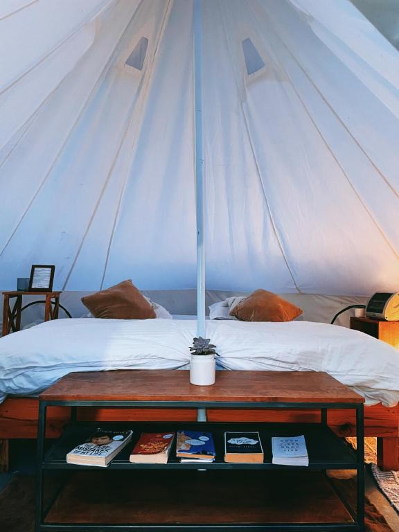 a tent with a bed and a table with books at Bell Glamping by The HULYA since 2021 in Mukteshwar