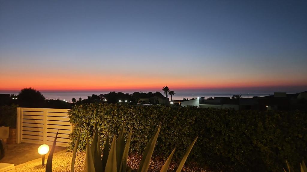 a sunset over a fence with a cactus at I due Ulivi Cornino in Custonaci