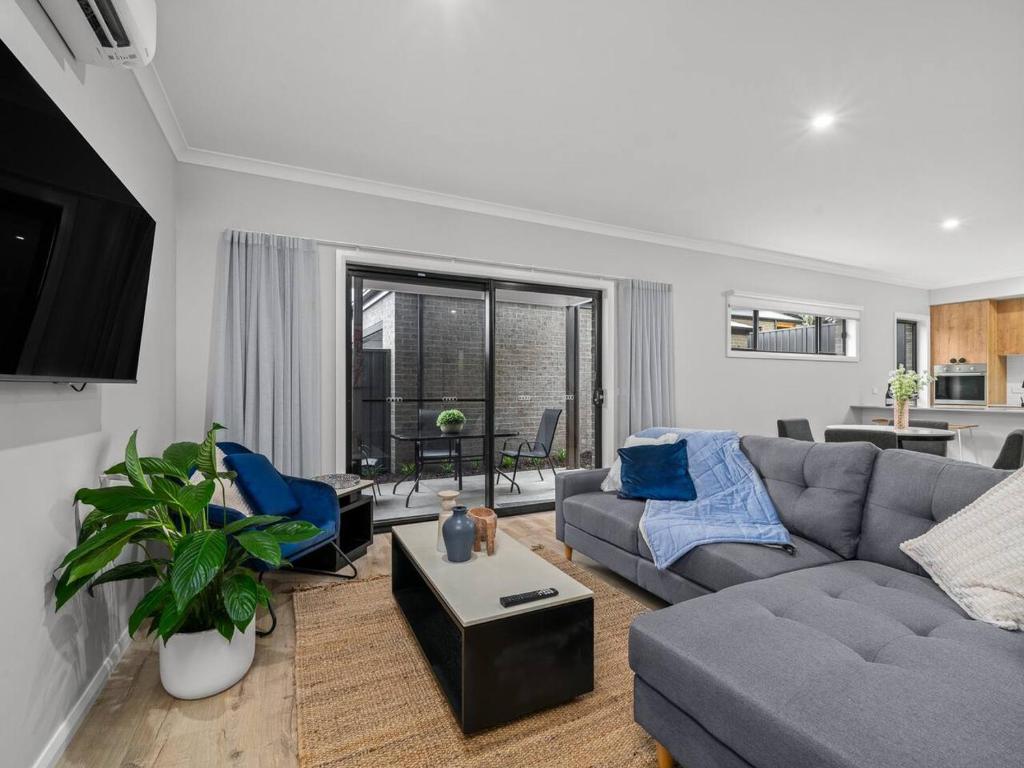 a living room with a gray couch and blue chairs at New Central 2 bedroom townhouse in Beechworth
