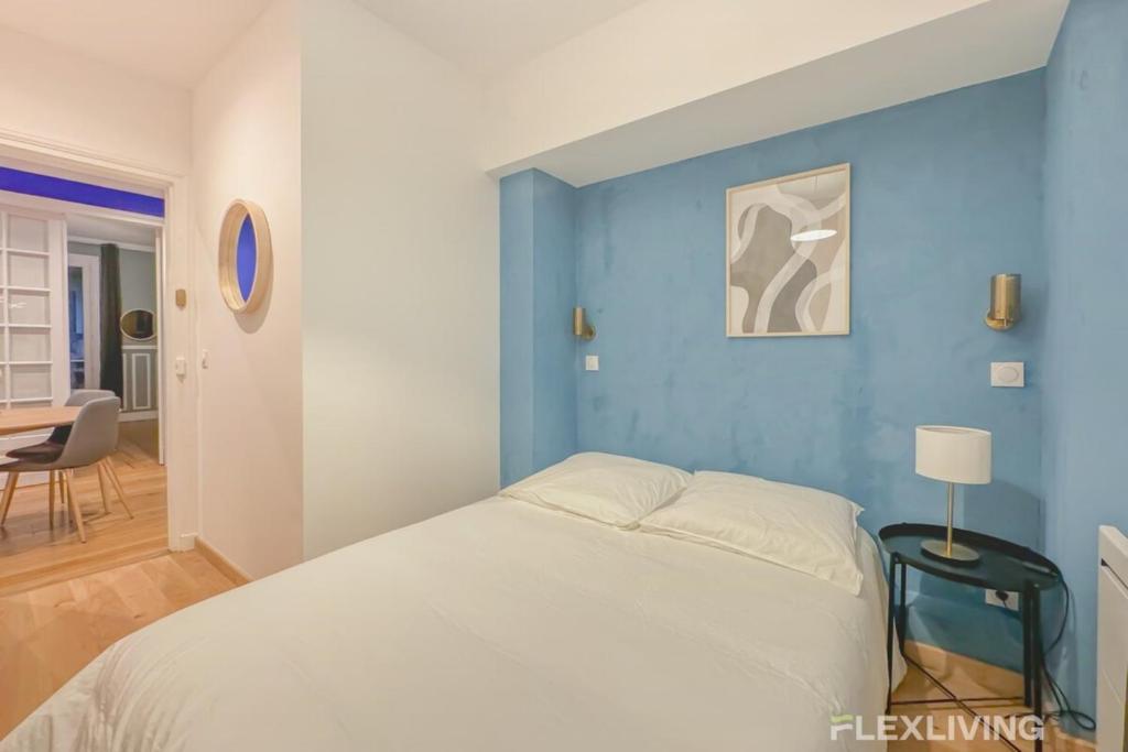 ein Schlafzimmer mit einer blauen Wand und einem Bett in der Unterkunft Flexliving - room - Neuilly-sur-Seine in Neuilly-sur-Seine