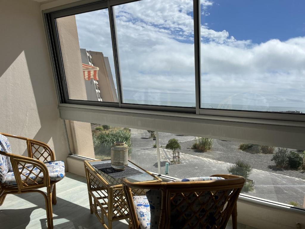 une pièce avec une table et des chaises et une grande fenêtre dans l'établissement L Arc en Ciel, à Saint-Jean-de-Monts