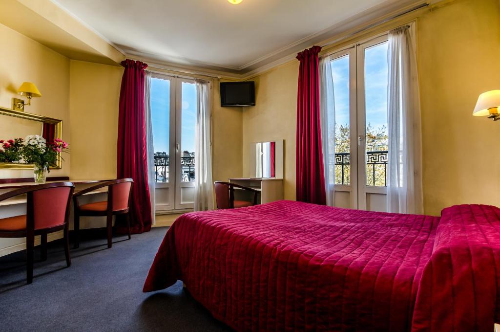 パリにあるアヴニール ホテル モンマルトルの赤いベッドとテーブルが備わるホテルルームです。