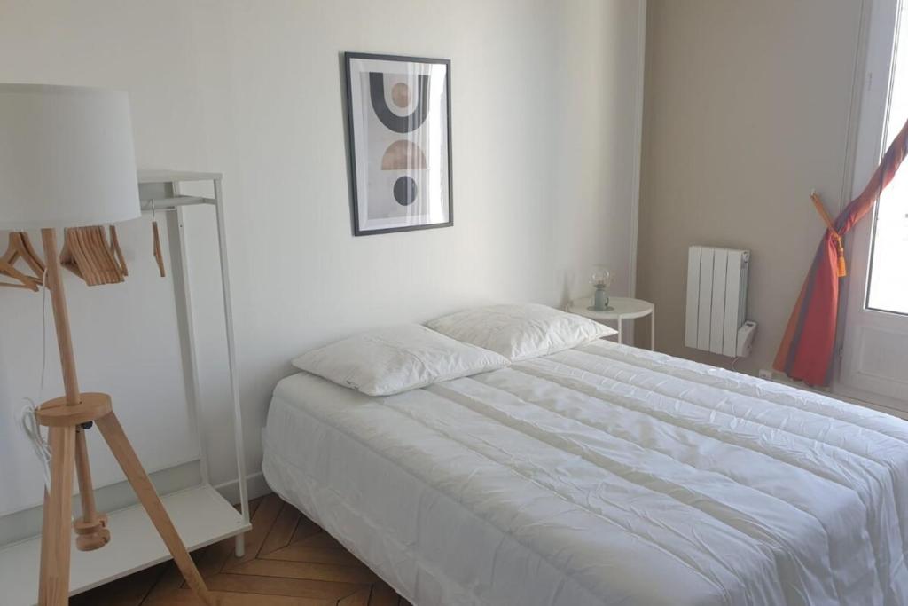 - une chambre blanche avec un lit et une lampe dans l'établissement Flexliving - room - Voltaire, à Paris