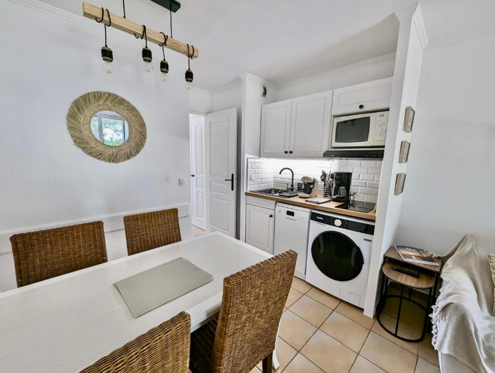 - une cuisine avec une table et des chaises blanches dans l'établissement Les Restanques 2058 rez de jardin, à Grimaud