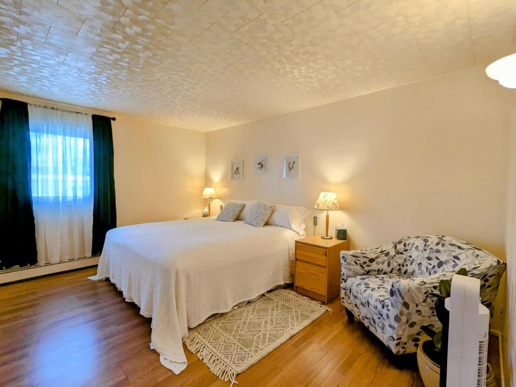 a bedroom with a white bed and a chair at Fireweed Apartments in Fairbanks