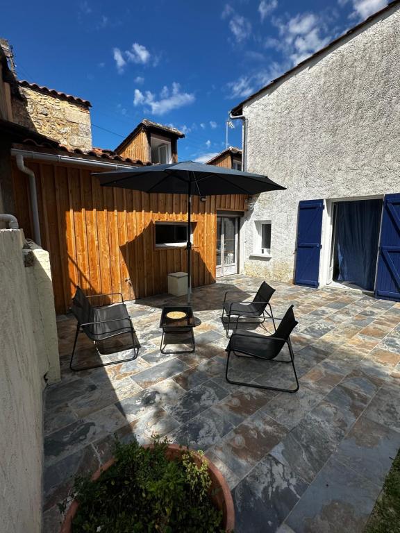 eine Außenterrasse mit Stühlen und einem Sonnenschirm in der Unterkunft Charmante maison de 4 chambres in Bergerac