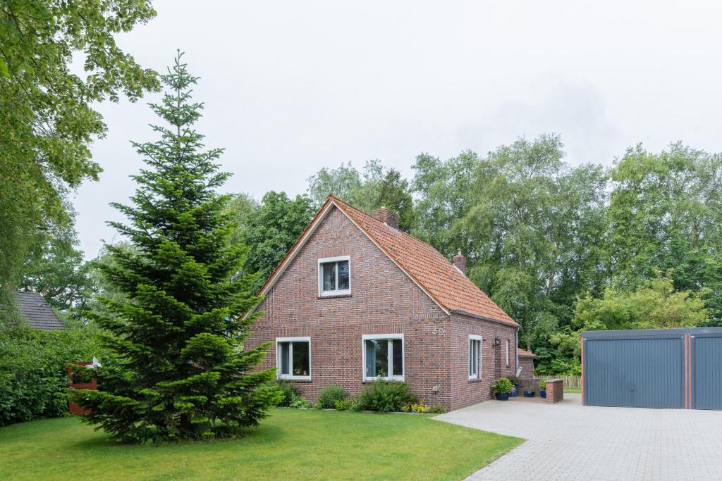a brick house with a tree in the yard at Huus de Freese 35224 in Beningafehn