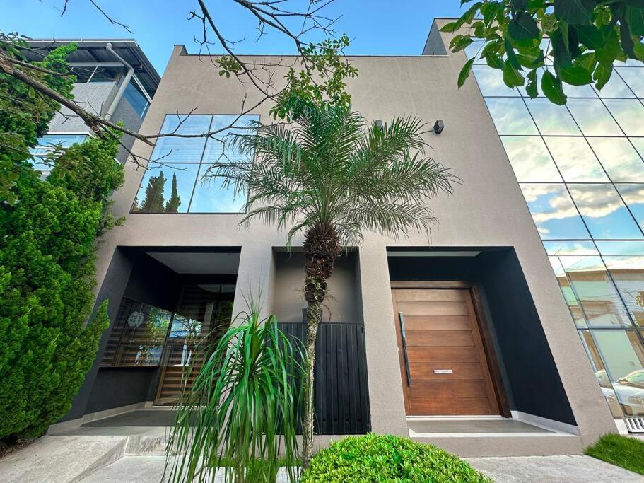 a palm tree in front of a house with a door at Casa Design Privacidade Familiar in Balneário Camboriú
