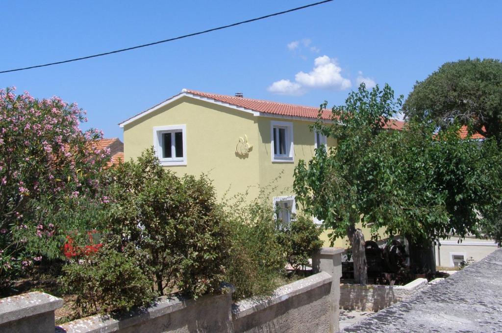 a yellow house with a fence in front of it at Apartments Buturić in Sali