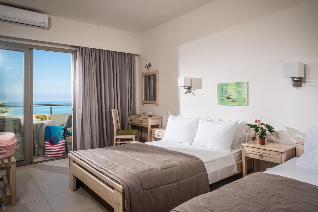 a hotel room with two beds and a balcony at Malliotakis Beach Hotel "by Checkin" in Stalida