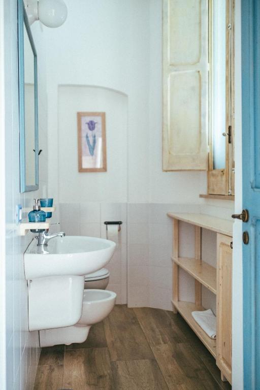 uma casa de banho branca com um lavatório e um WC em Elementa em Conversano