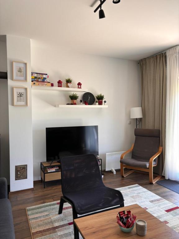 un soggiorno con TV, tavolo e sedie di Apartman PLAY Divčibare - 2 spavaće sobe a Divčibare