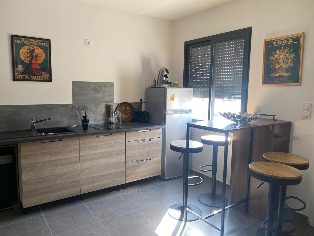 La cuisine est équipée d'un réfrigérateur et de tabourets de bar. dans l'établissement Appartement - Le Seven, à Uzès