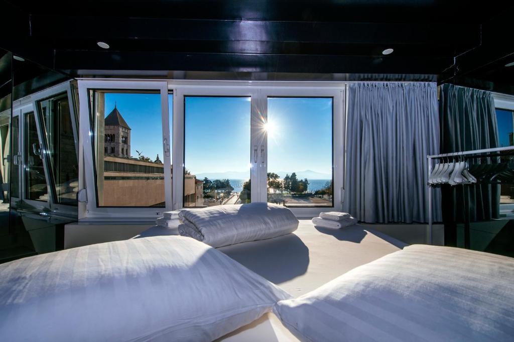 two beds in a room with a large window at Boutique Hostel Forum in Zadar