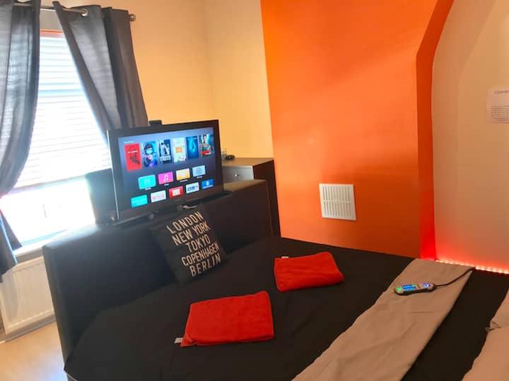 曼彻斯特King TV-Bed En-suite MediaCity, MUFC, Salford的一间卧室配有一张带红色枕头的床和一台电视。