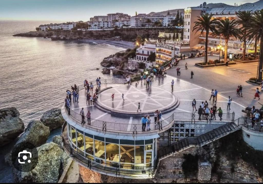 een groep mensen die rondlopen in een gebouw naast de oceaan bij El balcón de Nerja in Nerja