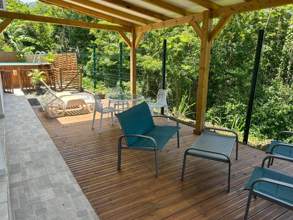 a wooden deck with chairs and a table on it at Location Vacances in Deshaies