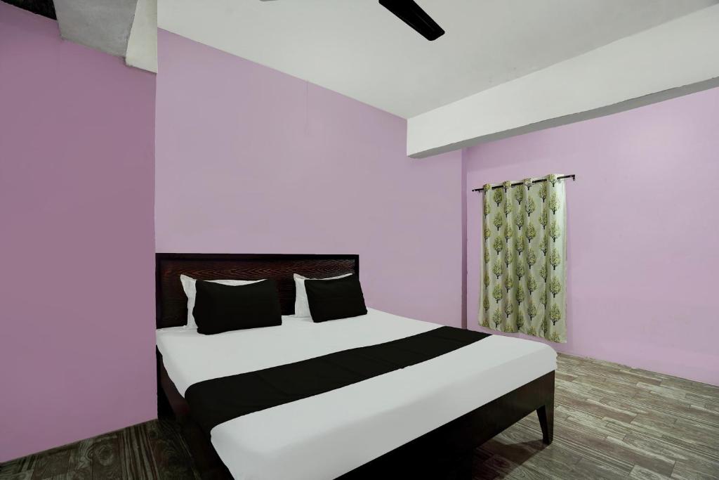 a bedroom with a bed with white and pink walls at SPOT ON MR Guest House in Rudrapur