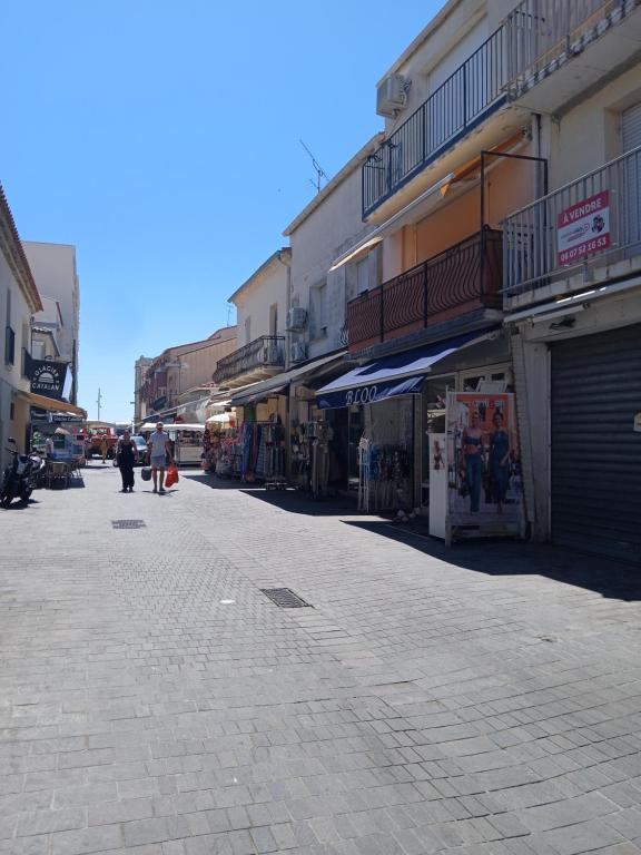 an empty street with buildings and people walking down the street at Appartement centre ville à deux pas de la plage in Le Grau-du-Roi