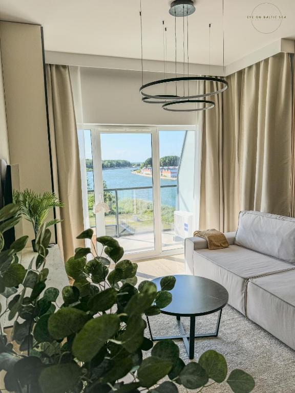ein Wohnzimmer mit einer Couch und einem Tisch in der Unterkunft Brand-New Apartment EYE ON BALTIC SEA Luxurious Spa Escape in Dziwnów with Stunning Views in Dziwnów