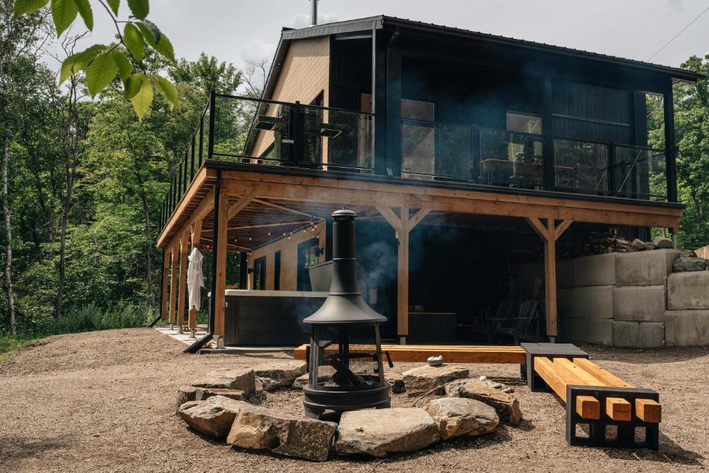 a house with a fireplace in the middle of a yard at Chalet Elva Nature & SPA in Sainte Béatrix