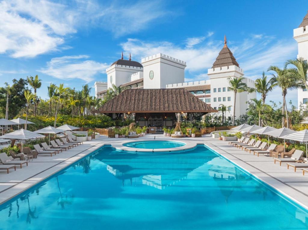 ヌエボ・バジャルタにあるBON Park Hotel at VidantaWorld Nuevo Vallartaの椅子とパラソルのあるリゾートのプール