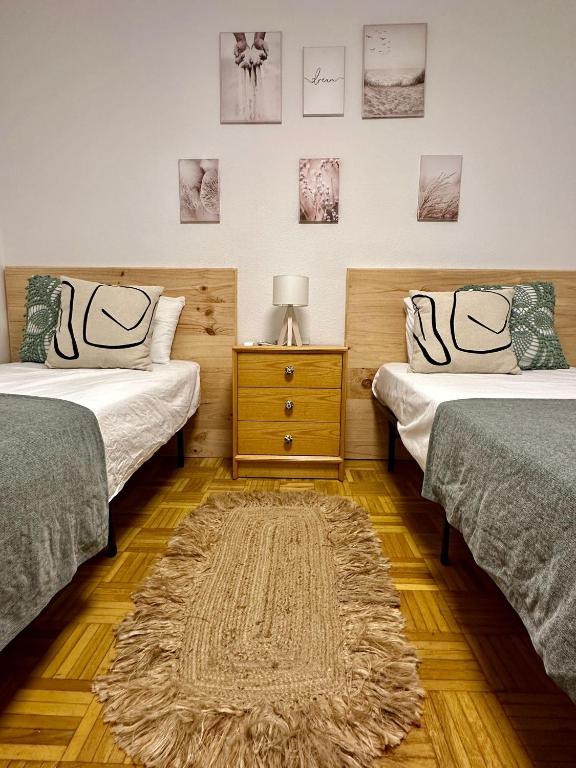 two beds in a room with a rug on the floor at Apartamento a 10 minutos de la Calle Laurel in Logroño