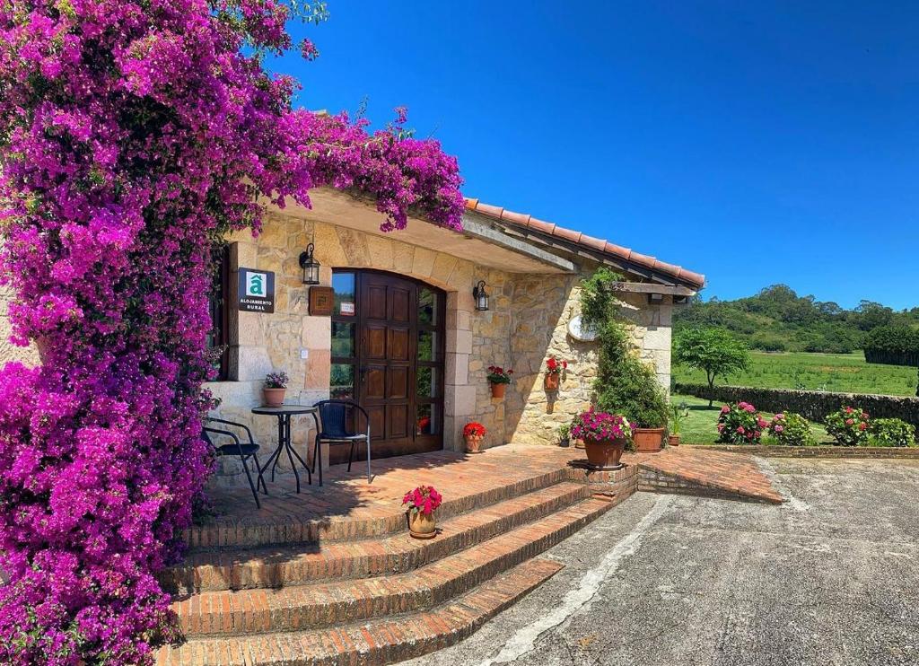 a house with purple flowers on the side of it at Posada La Roblera in Oreña