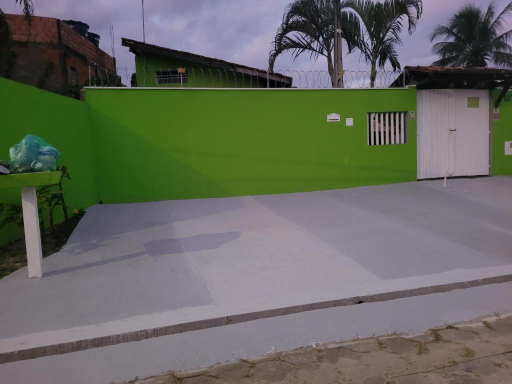 a green fence next to a parking lot at Casa inteira Chale e Edicula in Itanhaém