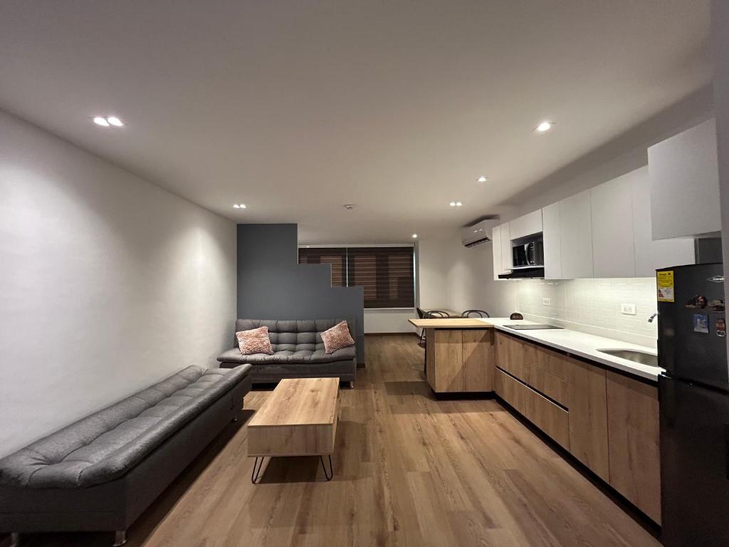 メデジンにあるAcogedor Apto a pasos del metro de Medellín zona centroのソファとテーブルのあるキッチンとリビングルーム
