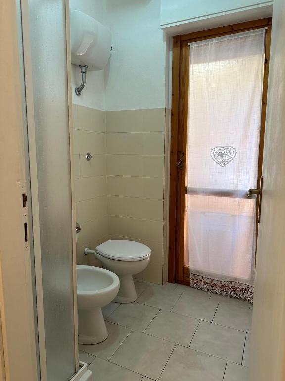 a bathroom with a toilet and a window at Villaggio Malfidano in Buggerru