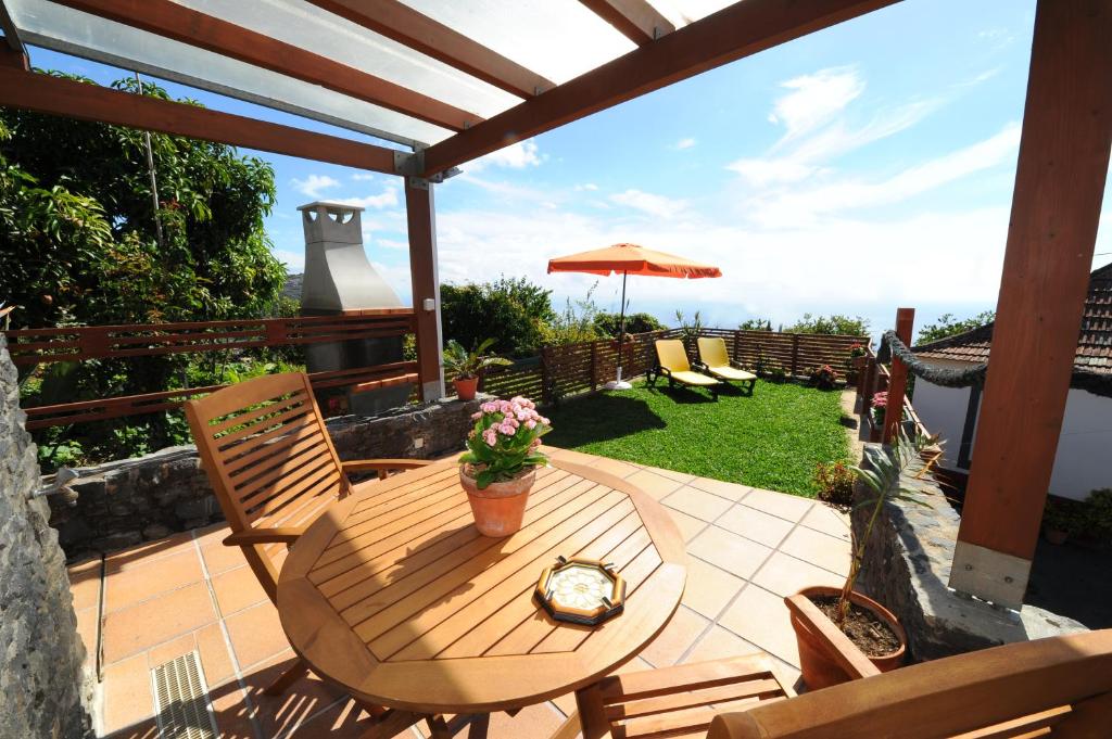 a wooden table with chairs and an umbrella on a patio at BHF Residences Bordadeira in Arco da Calheta