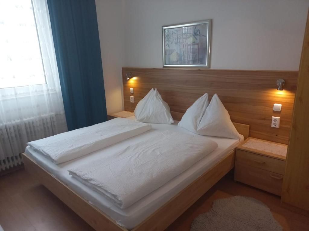 滨湖魏登Hotel Weidnerhof的卧室里有一张床，床单和枕头都是白色的